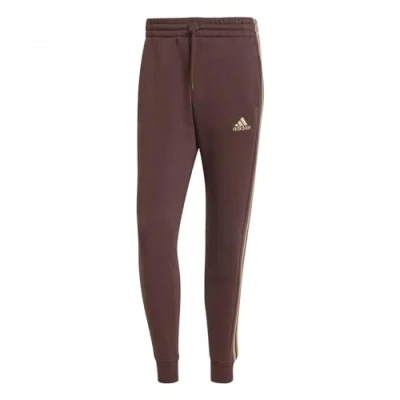 Abbildung von adidas Essentials Fleece Tapered Cuff 3 Stripes Pants, Herren Hose, Shadow Brown,