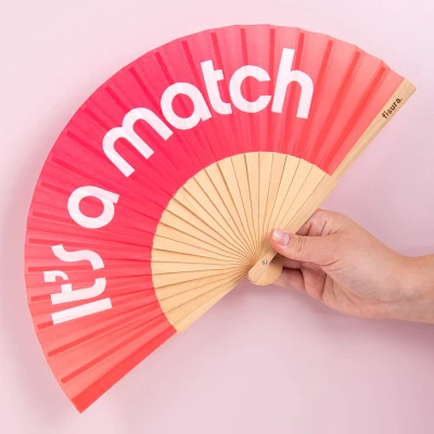 Abbildung von Fisura Holzfächer mit der Aufschrift &quot;It’s a match“. Trendiges Accessoire Farbverlauf in Rosa, moderner Handventilator aus Holz praktischem Aufhänger. Maße: 42,5 x 23 cm