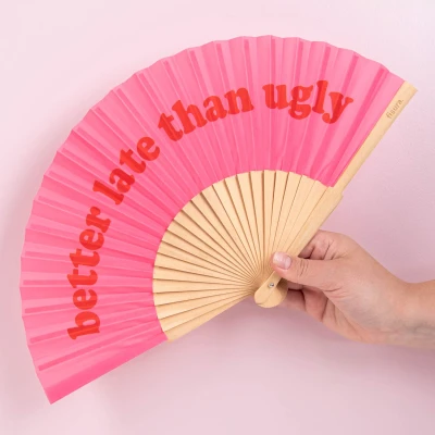 Abbildung von Fisura Moderner Holzfächer mit der Aufschrift &quot;better late than ugly“. Farbenfrohes, originelles Design, rosa roter Handventilator Aufhänger. Maße: 42,5 x 23 cm