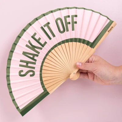 Abbildung von Fisura Handfächer aus Holz mit der Aufschrift &quot;Shake it off“. Farbenfrohes, modernes Accessoire in Rosa und Grün, tragbarer Ventilator praktischem Aufhänger. Maße: 42,5 x 23 cm